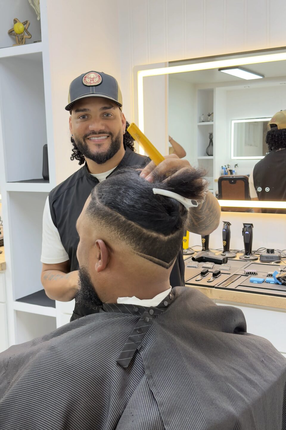 A smiling barber working on a client's sectioned hair