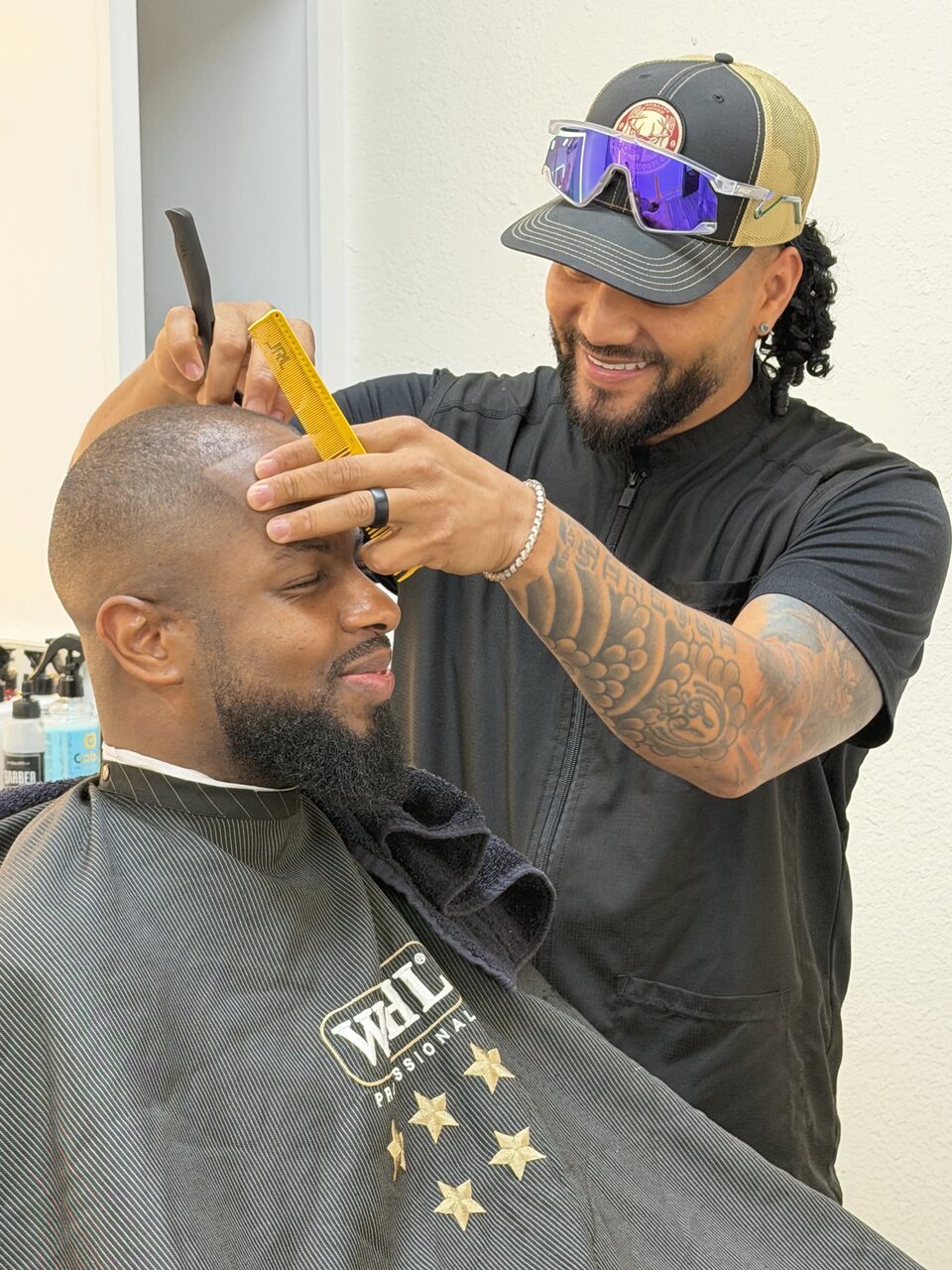 A barber using a comb and clippers to shape a client's short haircut
