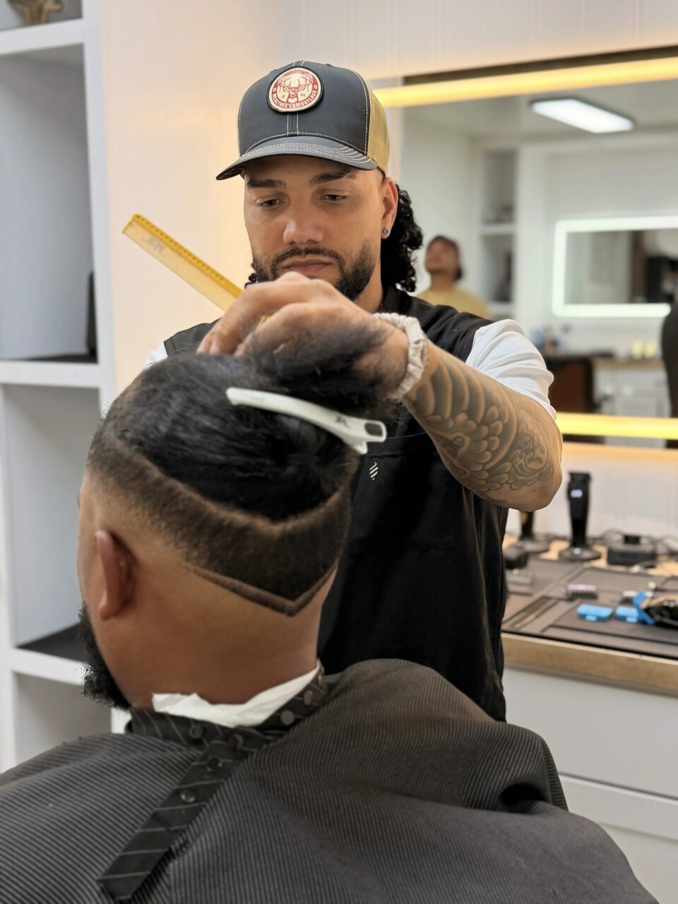 A barber combing a client's hair above a sharply defined shaved part