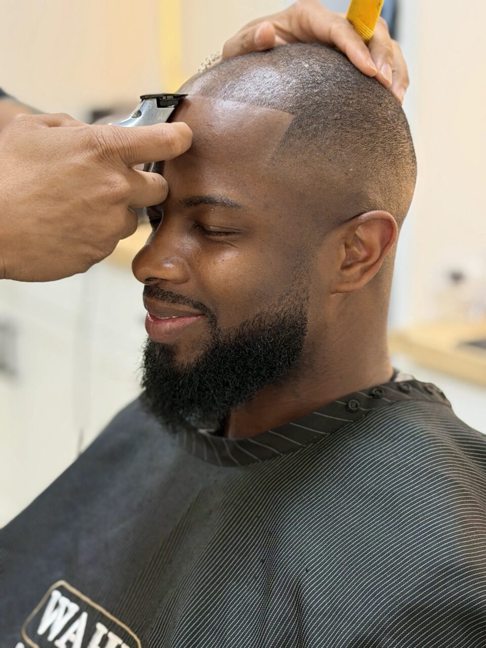 A barber using clippers to define a client's hairline