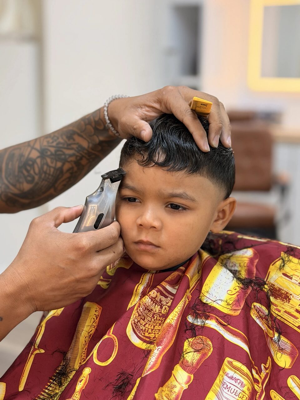 A barber trimming a young client's hair with clippers and a comb