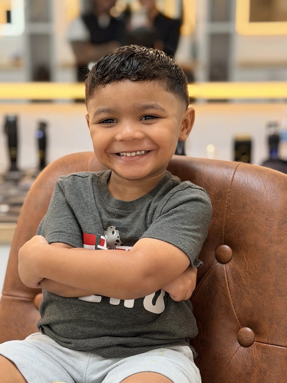 A smiling young client showing his fresh haircut in a leather barber chair