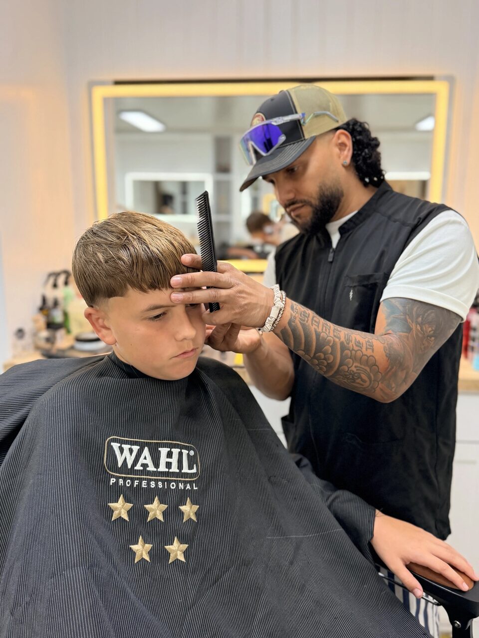 A barber carefully shaping a young client's fringe