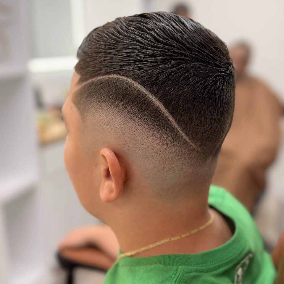 The back of a young client's haircut with a curved shaved part