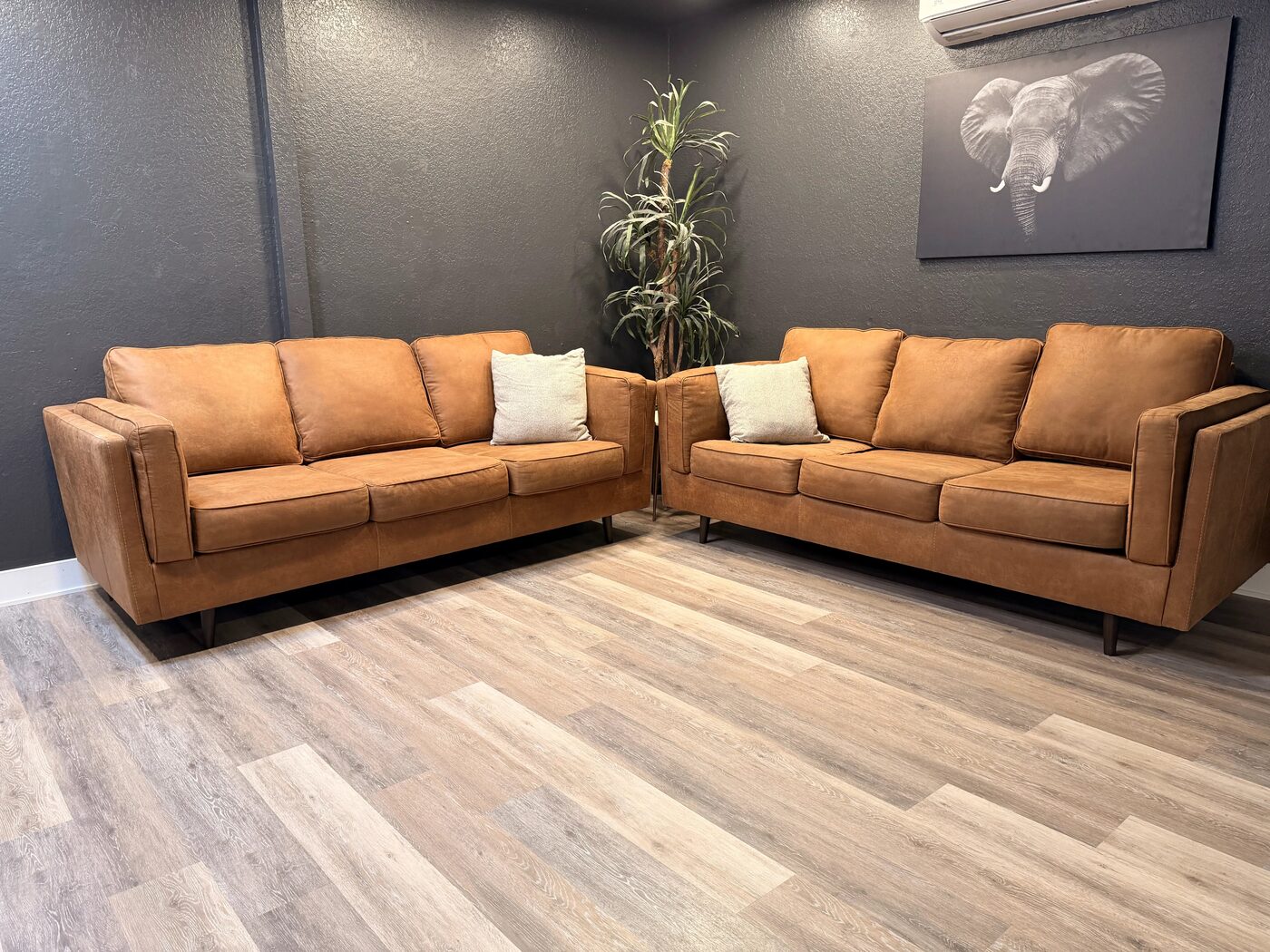 The client lounge with 2 camel leather sofas against a dark charcoal wall