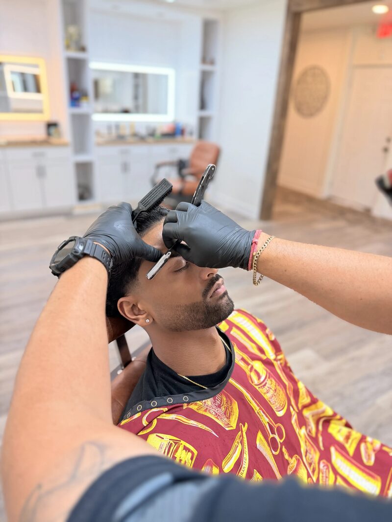A barber using a straight razor for precise brow detail
