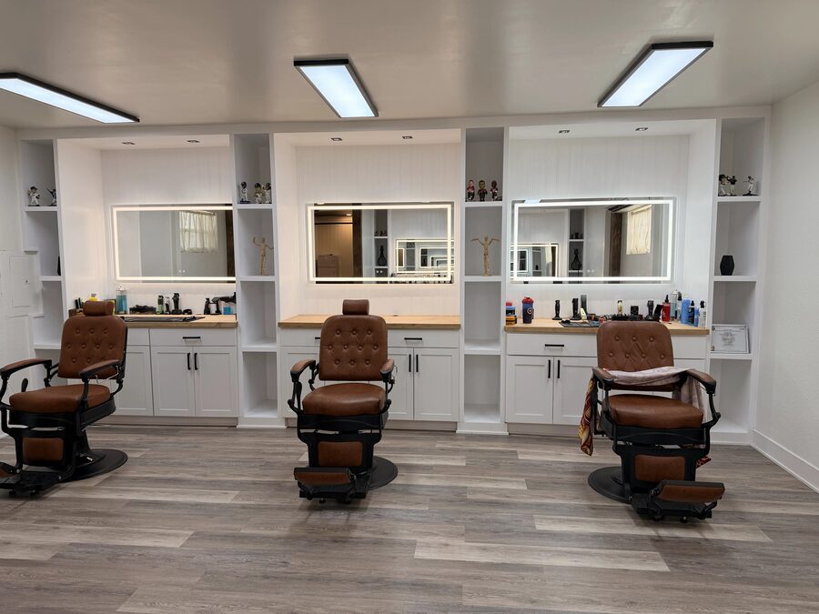 Three camel leather barber chairs arranged in front of illuminated mirrors