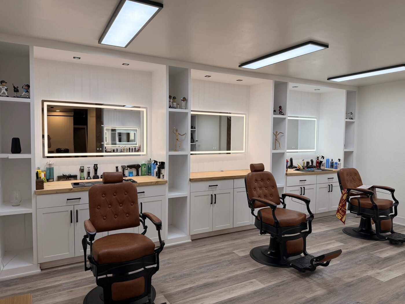 Camel leather barber chairs facing illuminated mirrors at One Refined Heritage