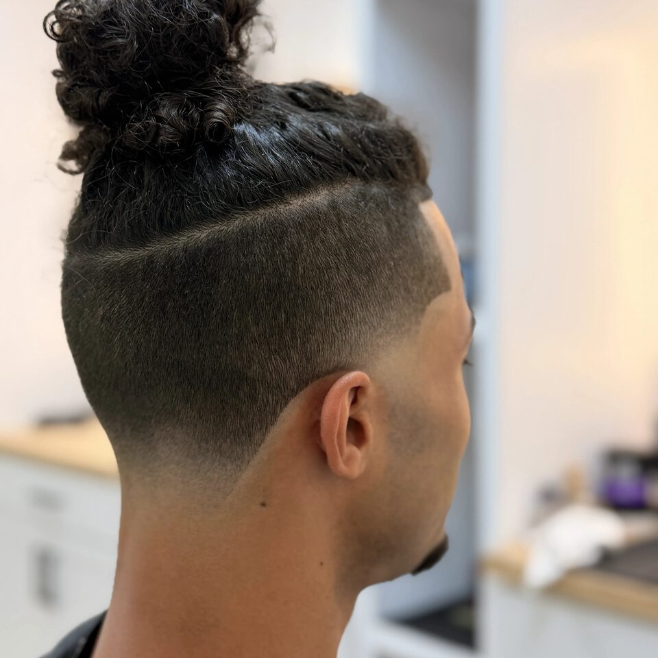 A top knot with closely tapered sides and a defined part, viewed from behind